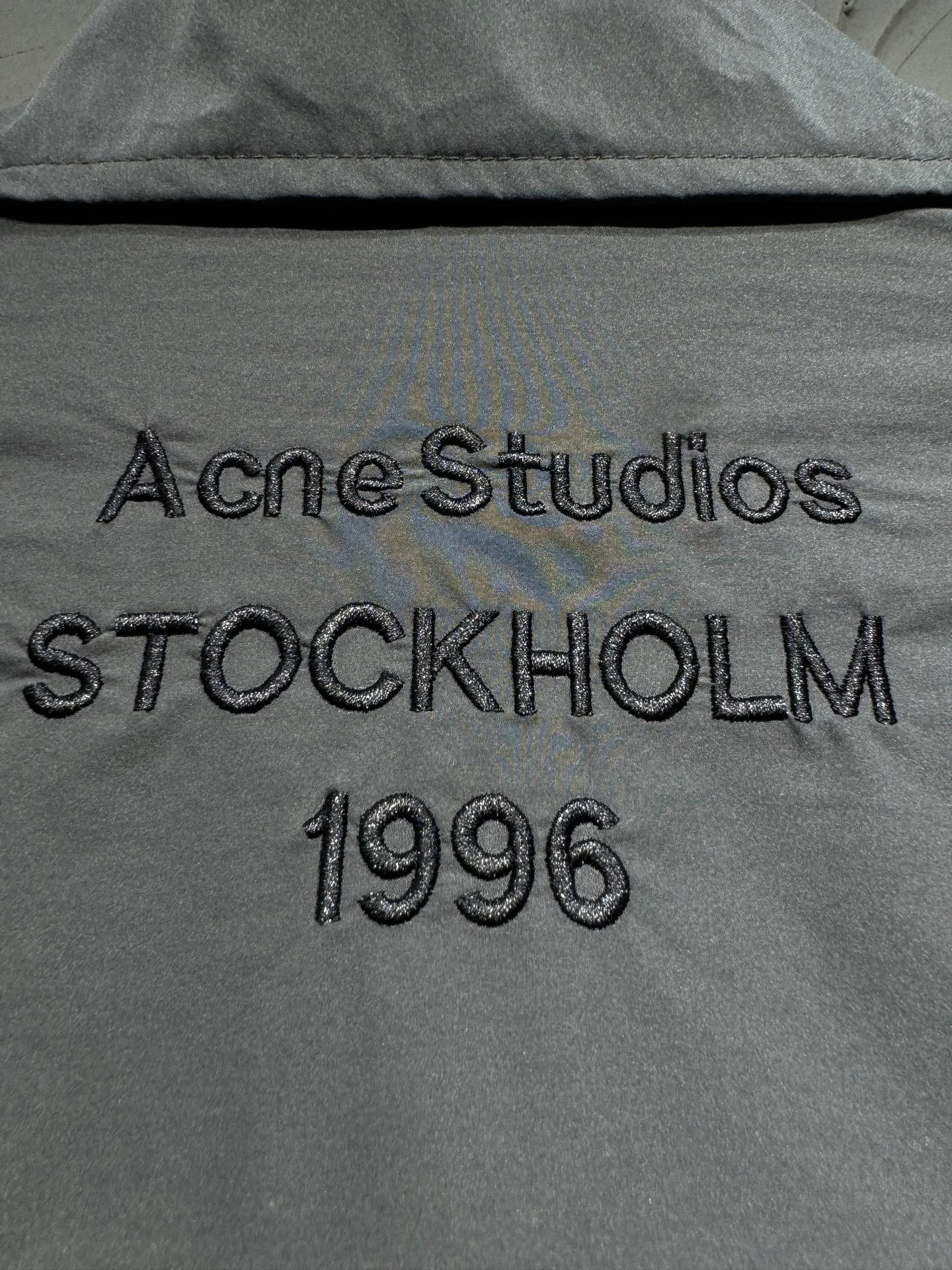 Acne Studios 26SS Large Lapel Short Jacket The fabric is made of 100% nylon (nylon/polyamide fiber) 75D high-density wrinkled nylon. The fabric has been permanently pressed and shaped by high temperature, and washed with high-pressure wrinkles at the factory to form its own irregular texture, permanently retaining the wrinkled texture, which will not disappear after washing. Matte matte coating removes the plastic glossy surface of nylon itself to create a low-key matte paper feel. Three-proof micro-coating, weak waterproof, anti-fouling, anti-static treatment, not easy to get dust. The interior is made of full-width mesh Breathable nylon lining, which reduces the stickiness of the nylon fabric to the body, improves air circulation, prevents sweating from sticking to the skin, and the zipper does not rub against the skin. The version adopts the raglan split topstitching process, and the front and rear panels are divided diagonally to expose even stitching. The three-dimensional dropped shoulders are loose and the fit is increased to increase the margin of movement. The back neckline is three-dimensional and high-density computer embroidered, and the embroidery lines are dense and not prickly. Customized all-metal matte nylon zipper, Genuine Leather embossed brand letters on the zipper leather tab, zipper tape with same color nylon fit to the body, double-locked reinforcement on both sides of the zipper to prevent pulling and tearing. Color: Gray Size: S M L